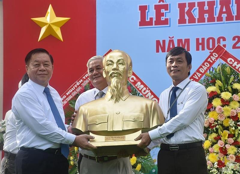 Bí thư Trung ương Đảng, Trưởng ban Tuyên giáo Trung ương Nguyễn Trọng Nghĩa (trái) tặng bức tượng chân dung Chủ tịch Hồ Chí Minh cho đại diện lãnh đạo Trường THPT Trương Định, Tiền Giang